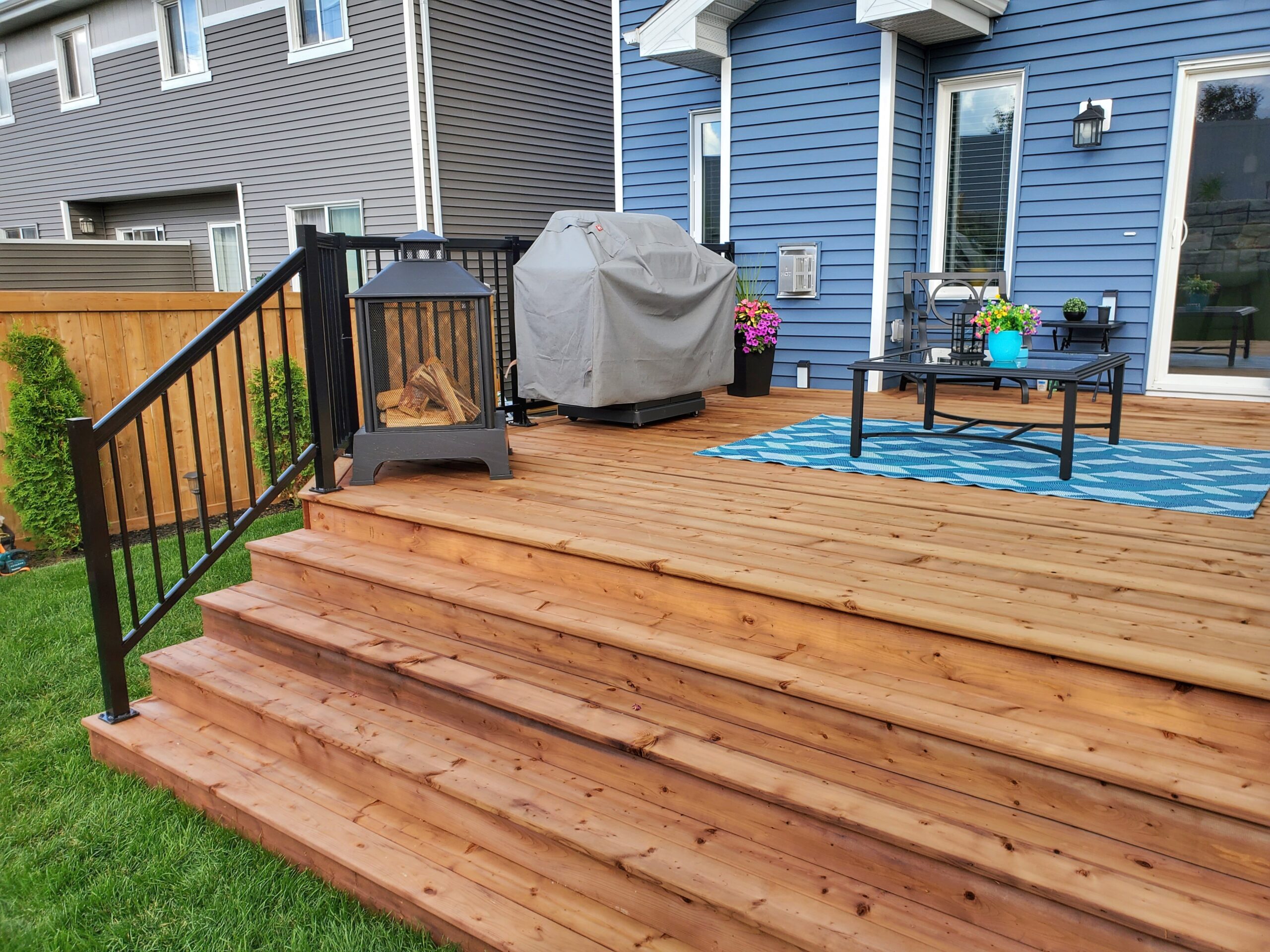 Stained cedar deck with wide stairs and aluminum railing built by Crestfield Decking in Edmonton, Alberta