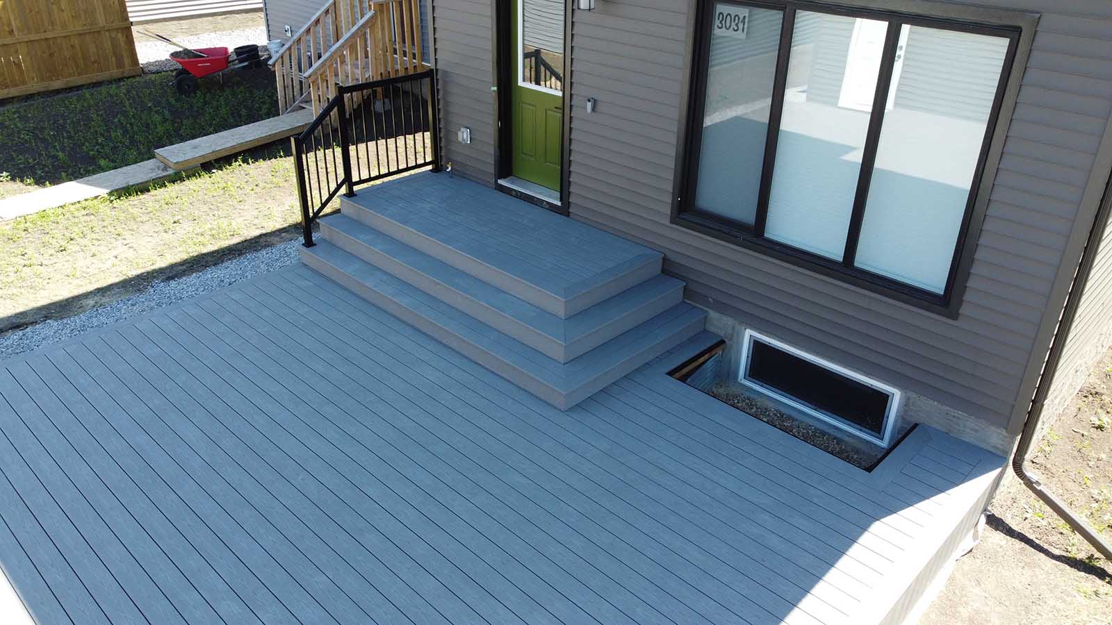 Grey composite deck with front steps and full backyard coverage built by Crestfield Decking in Edmonton, Alberta