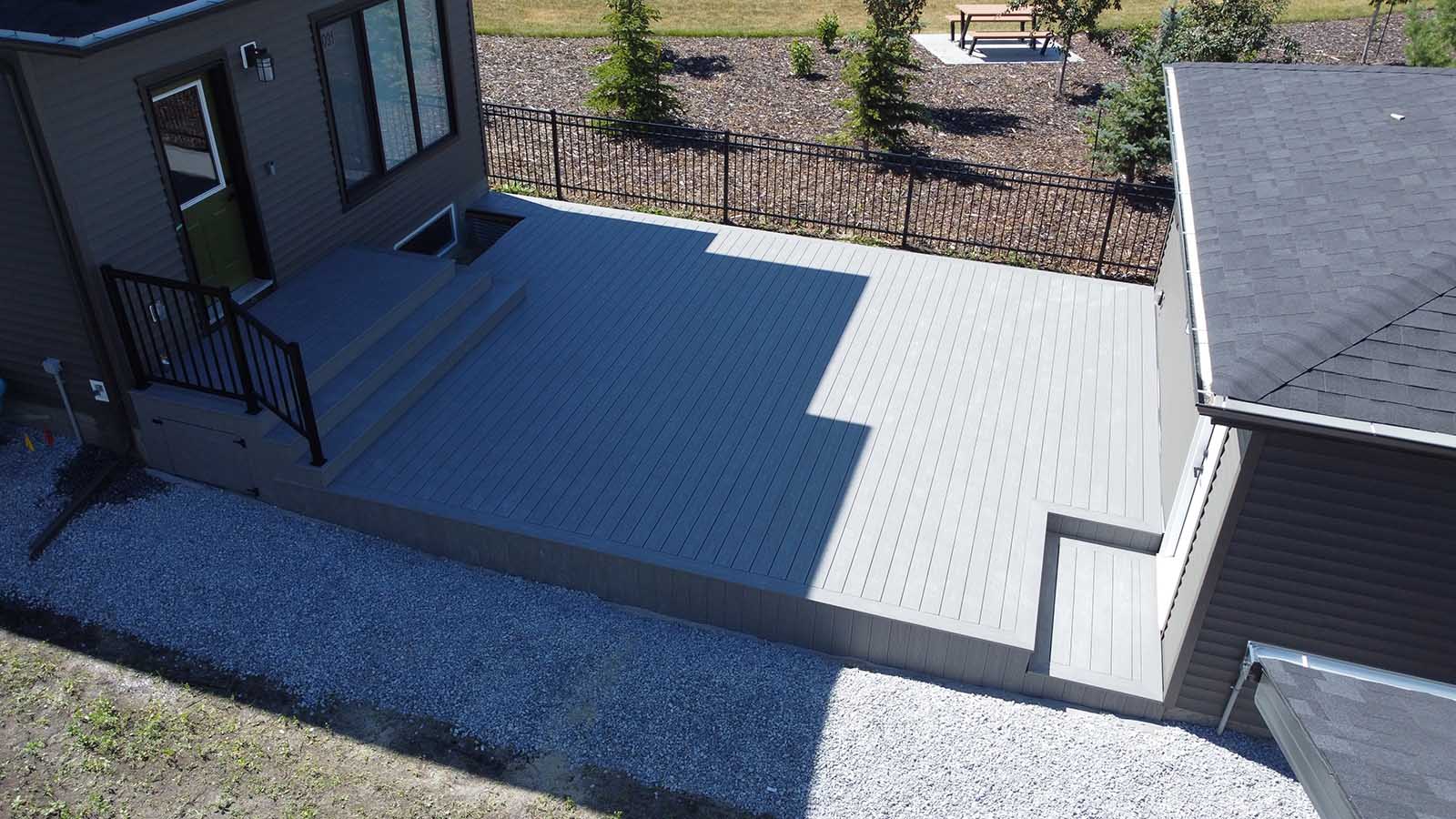 Wide aerial view of grey composite deck covering backyard between house and garage built by Crestfield Decking in Edmonton, Alberta