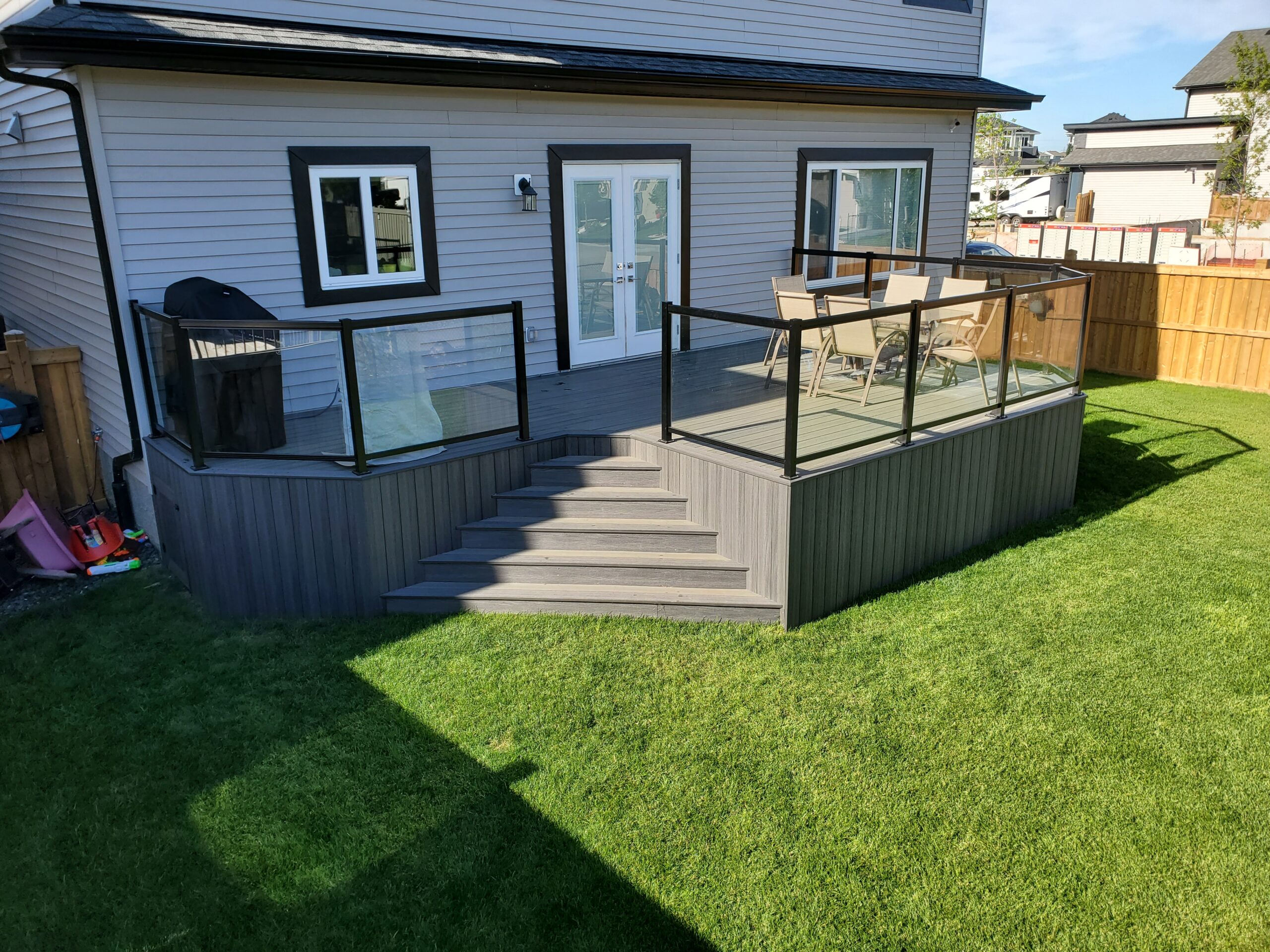 Composite deck with black aluminum and glass railing viewed from the backyard in Edmonton, Alberta