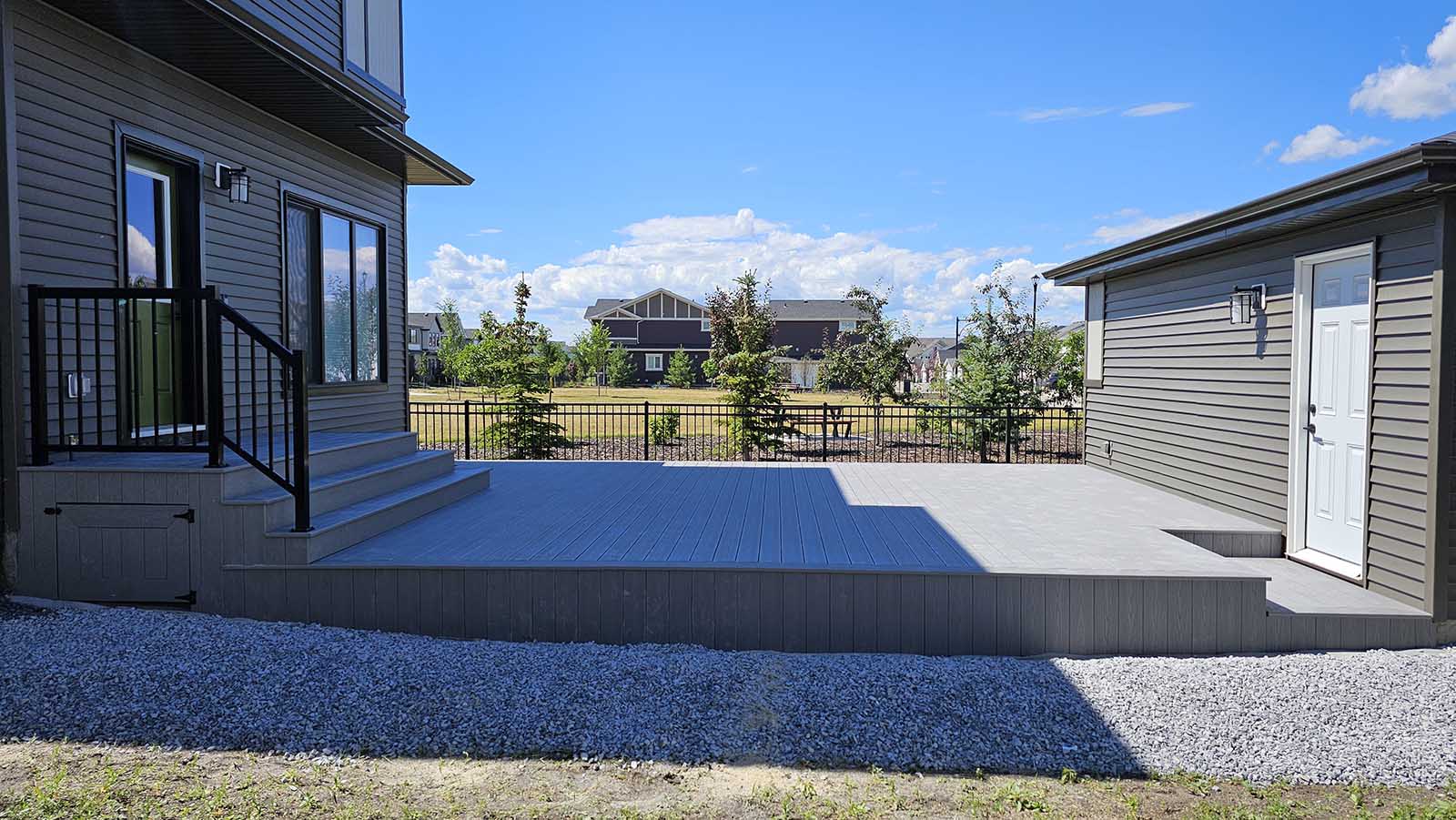 Grey composite deck connecting house to garage with composite skirting built by Crestfield Decking in Edmonton, Alberta