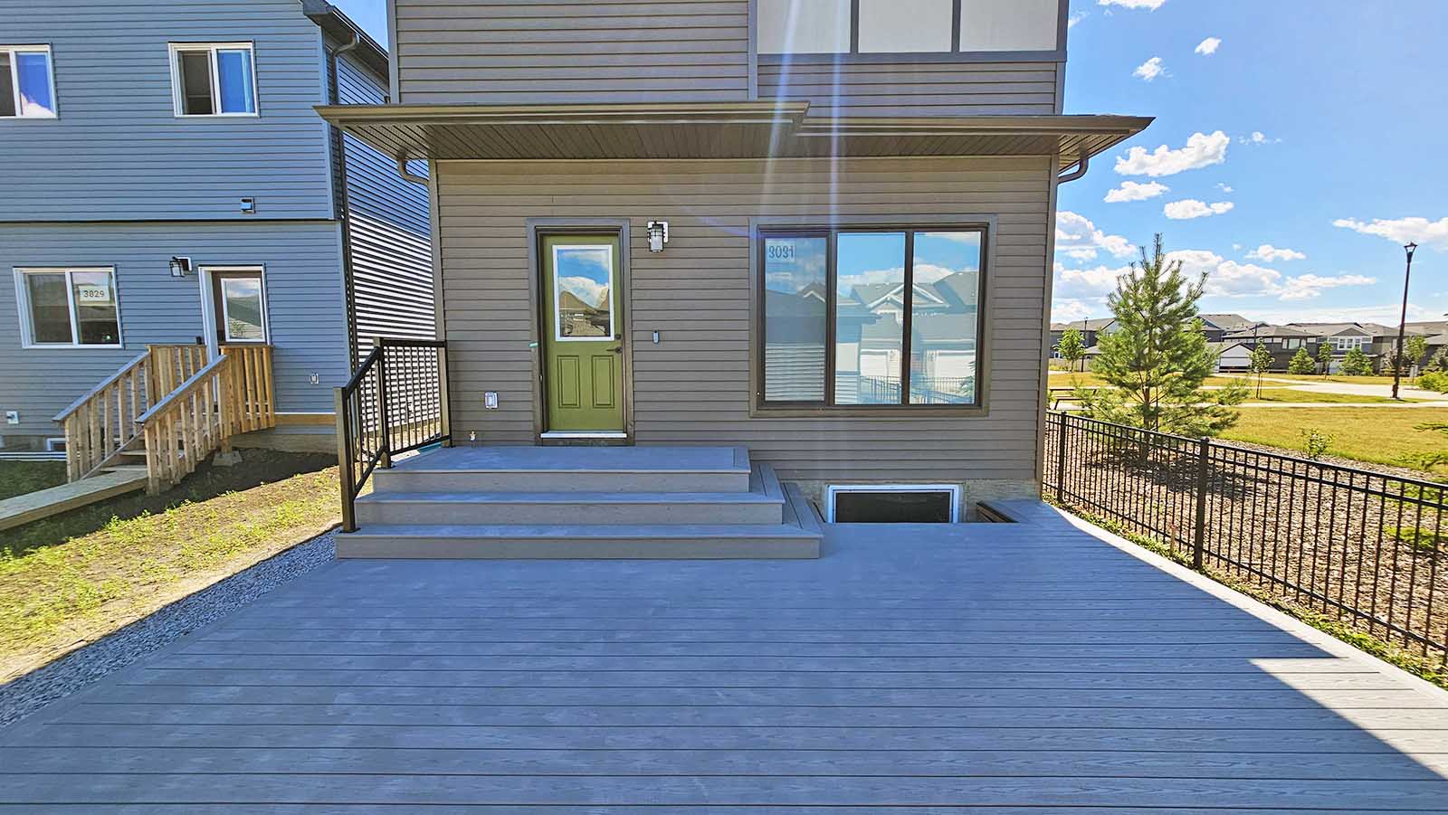 Front view of grey composite deck with stairs and black aluminum railing built by Crestfield Decking in Edmonton, Alberta
