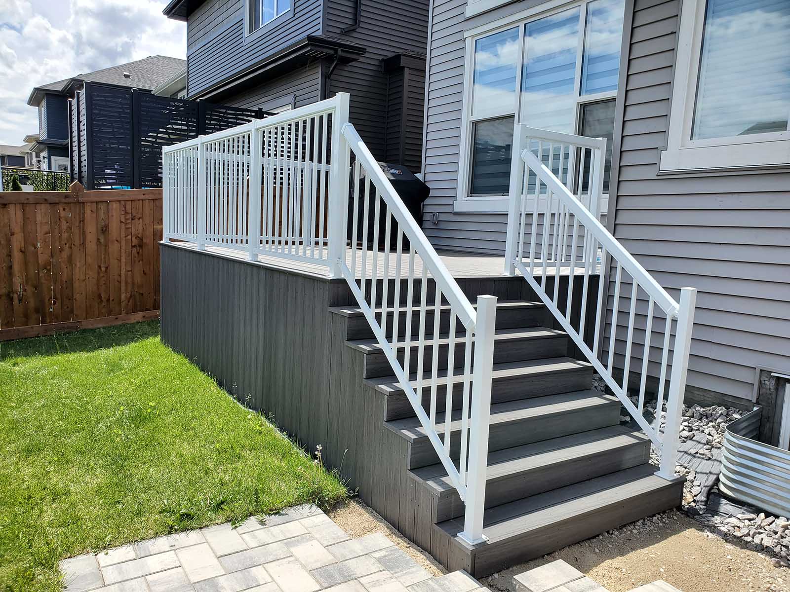 Grey composite deck with stairs and white aluminum picket railing built by Crestfield Decking in Edmonton, Alberta