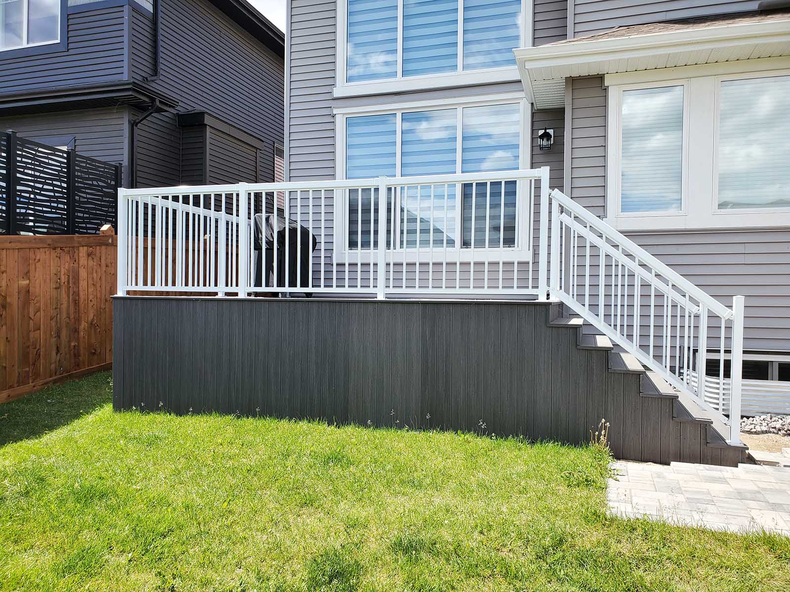 Side view of grey composite deck with white aluminum railing and composite skirting built by Crestfield Decking in Edmonton, Alberta