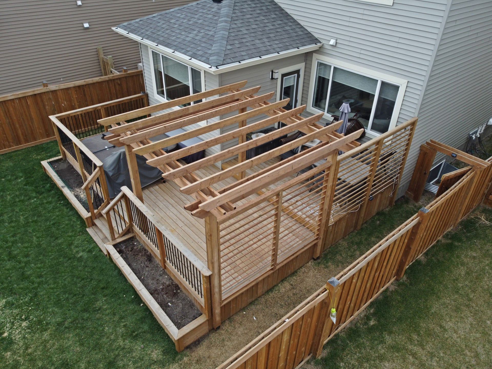 Custom deck with attached pergola and horizontal privacy wall in Edmonton backyard