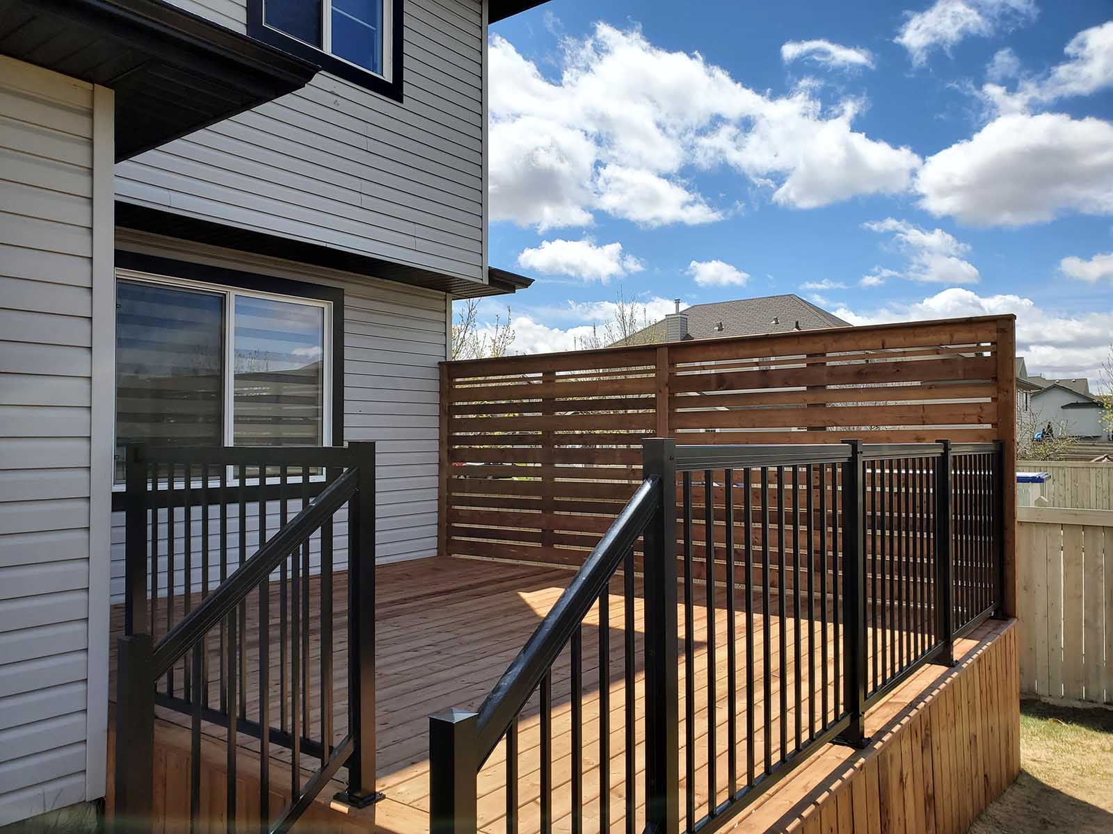 Close-up of pressure-treated deck with black aluminum railing and horizontal privacy screen built by Crestfield Decking in Edmonton, Alberta