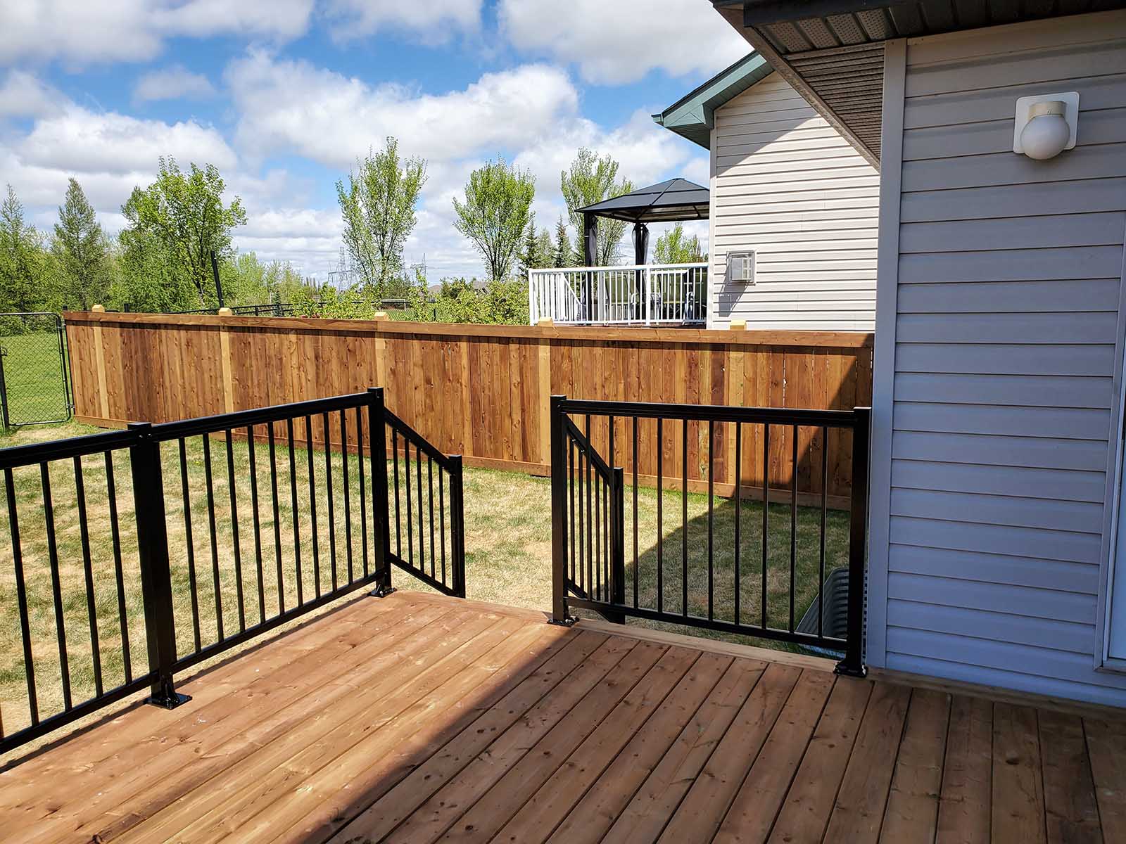 On-deck view of pressure-treated deck with black aluminum railing and privacy fence built by Crestfield Decking in Edmonton, Alberta