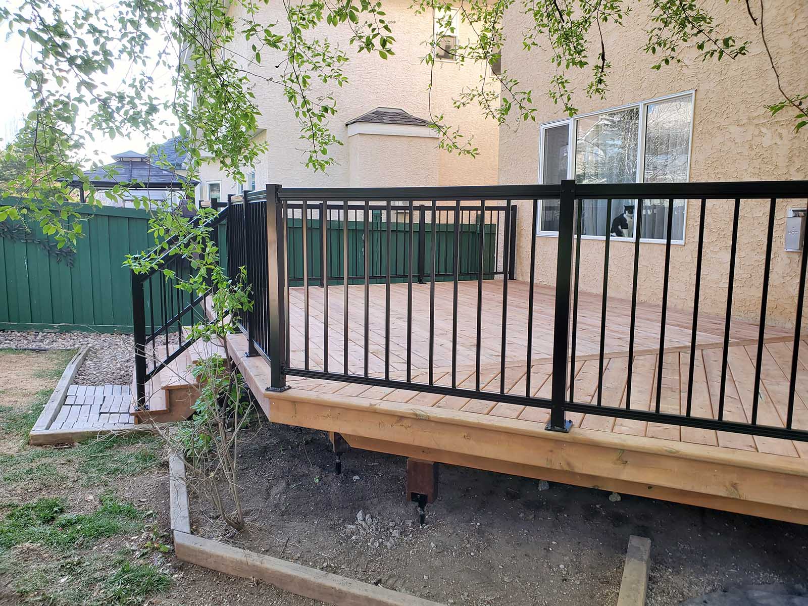 Side view of pressure-treated deck with black aluminum picket railing built by Crestfield Decking in Edmonton, Alberta