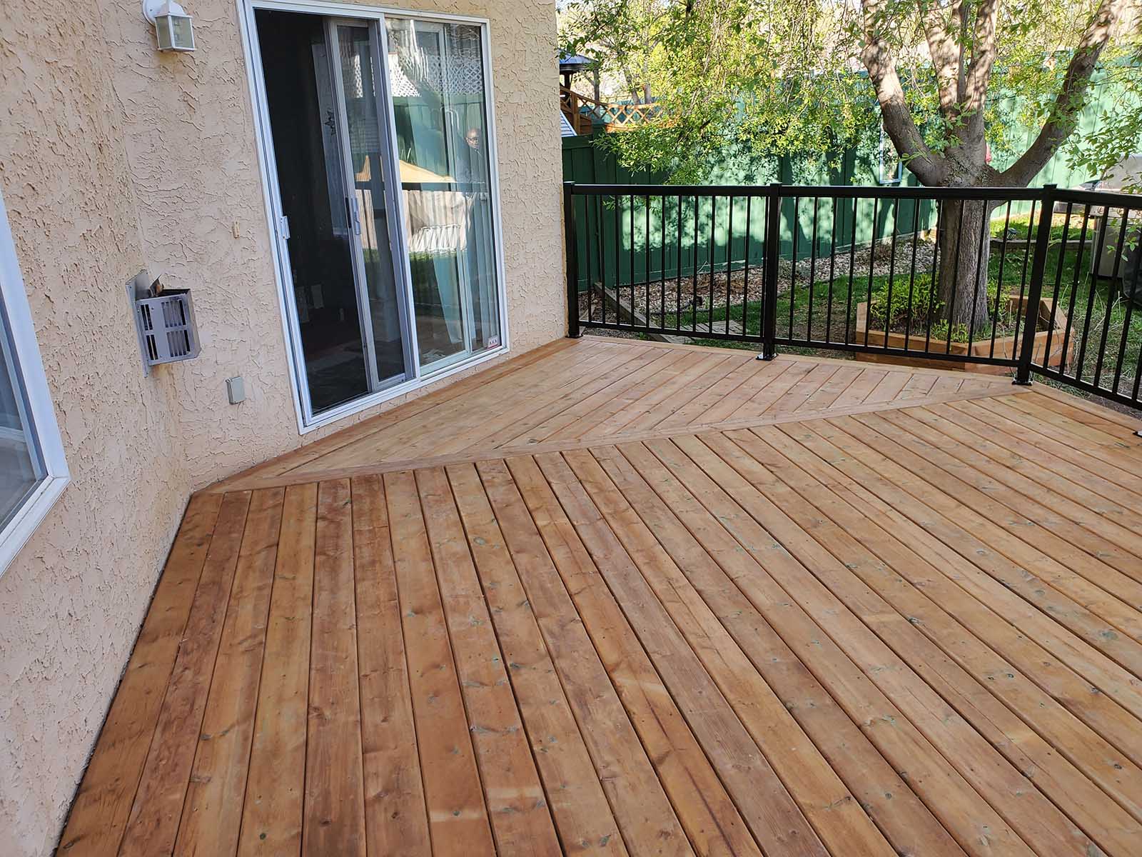 Pressure-treated deck with picture frame board pattern and black aluminum railing built by Crestfield Decking in Edmonton, Alberta