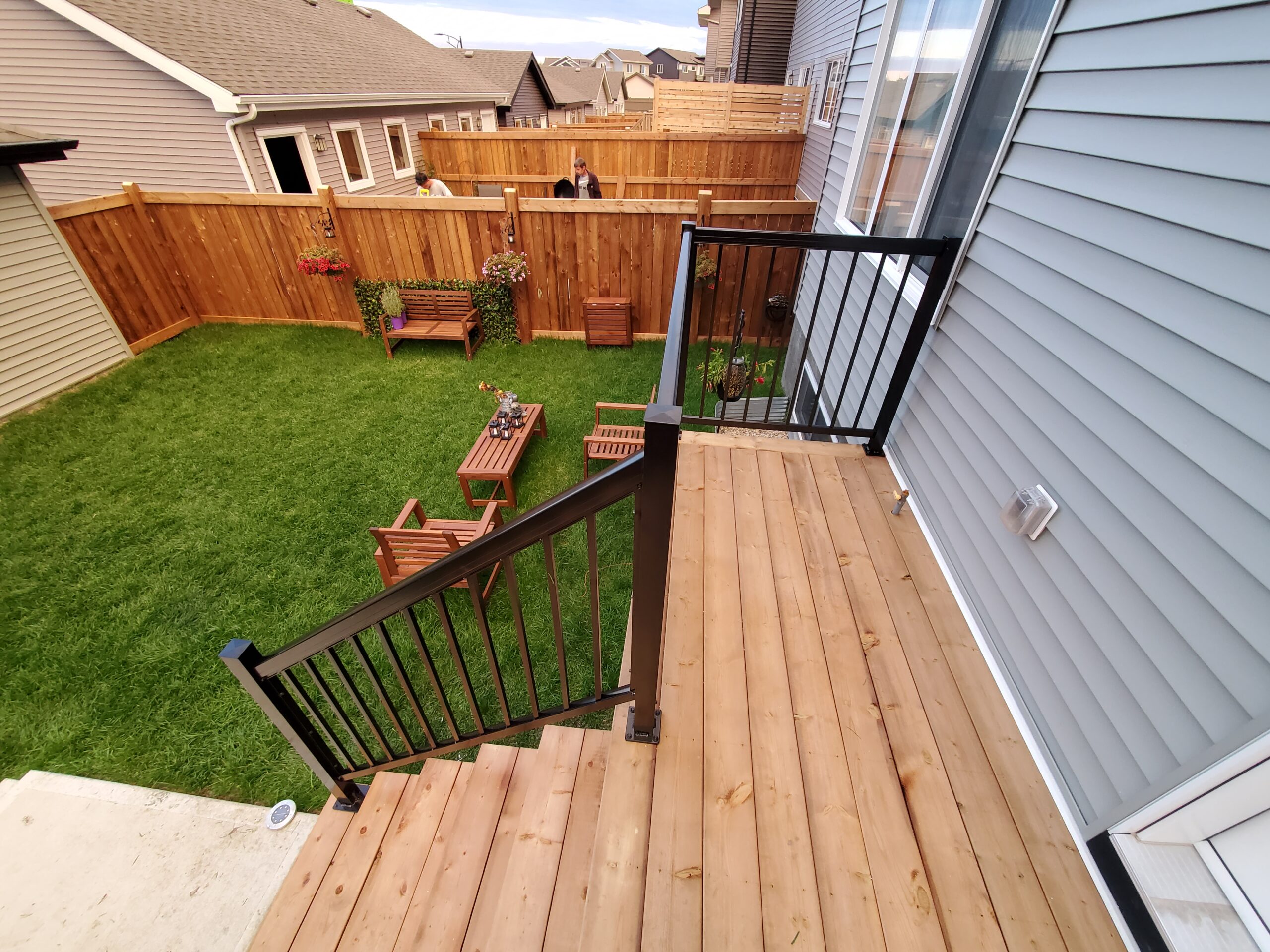 Pressure-treated deck with custom stairs and black aluminum railing for a backyard built by Crestfield Decking in Edmonton, Alberta