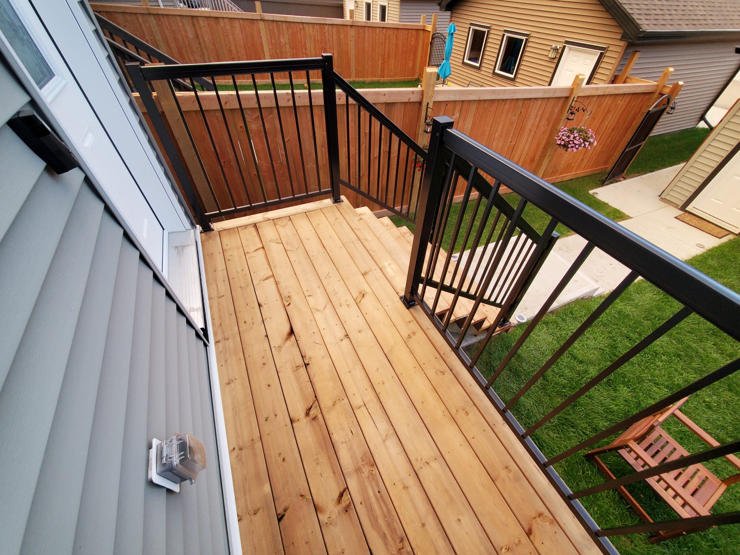 Small pressure-treated deck landing with black aluminum railing built by Crestfield Decking in Edmonton, Alberta
