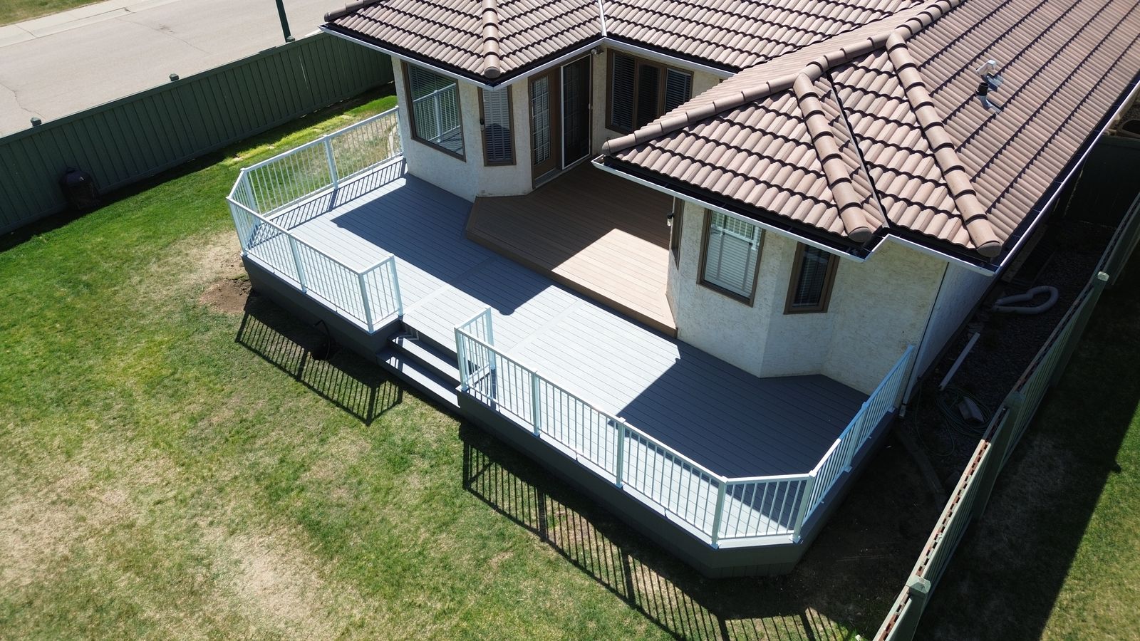 Two-tone composite deck with white aluminum picket railing and Maritime Grey and Coconut Husk decking in Wedgewood Heights, Edmonton, Alberta